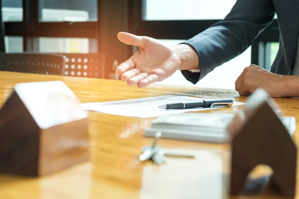 "Property lawyer gesturing across a desk towards an agreement, pen, keys and model houses, property law and conveyancing services in Toukley